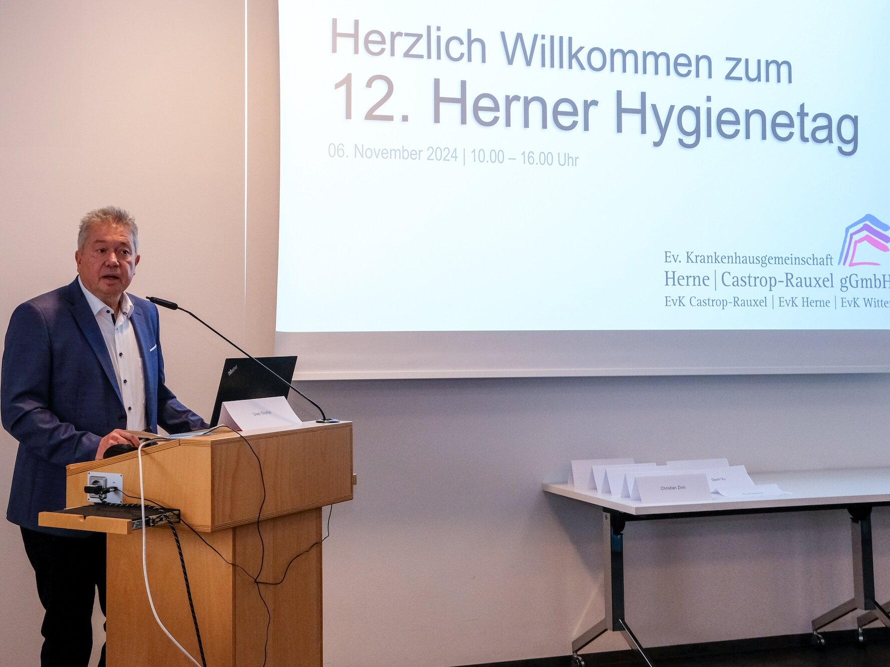 Ein Mann im blauen Anzug spricht auf einem Podium während des 12. Herner Hygienetages.